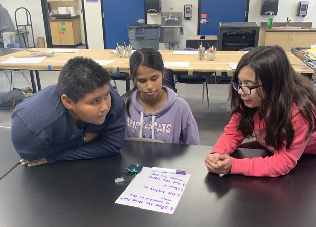 three students look at activity sheet