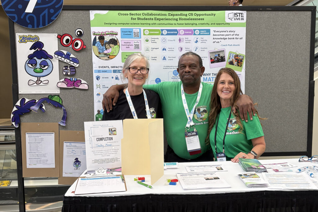 Two women and one man stand in front of colorful poster in conference center
