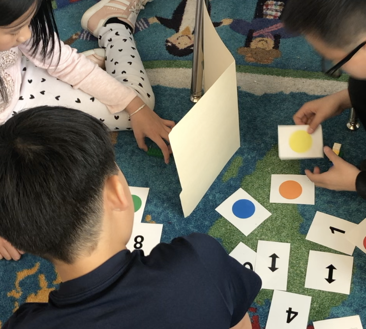 Three children sitting on the floor participating in a card based activity.