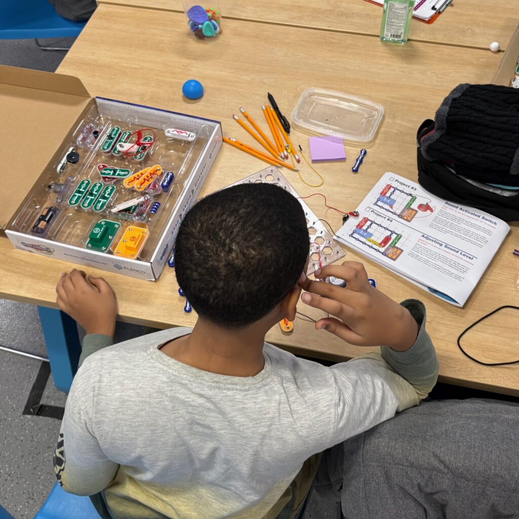 Middle school student at table working on Adruino breadboard activity.