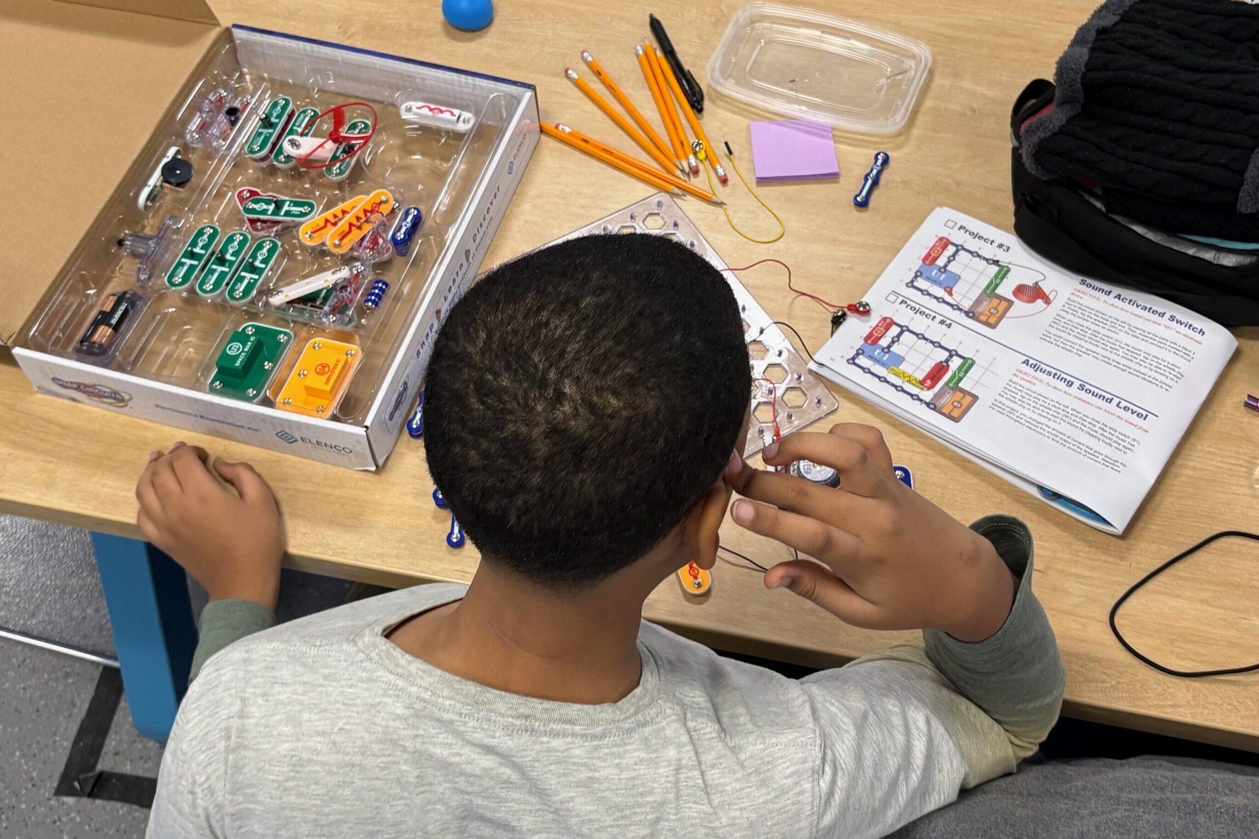 Middle school student at table working on Adruino breadboard activity.