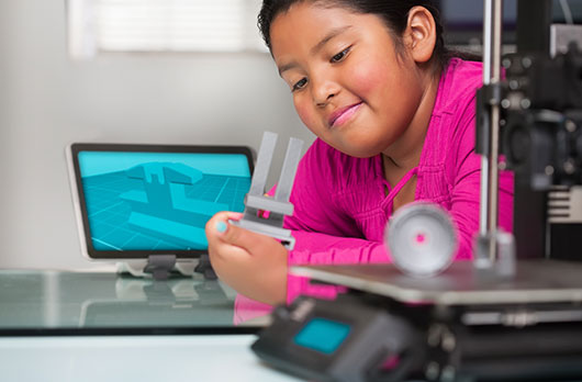 A younger girl looking at a 3D printer